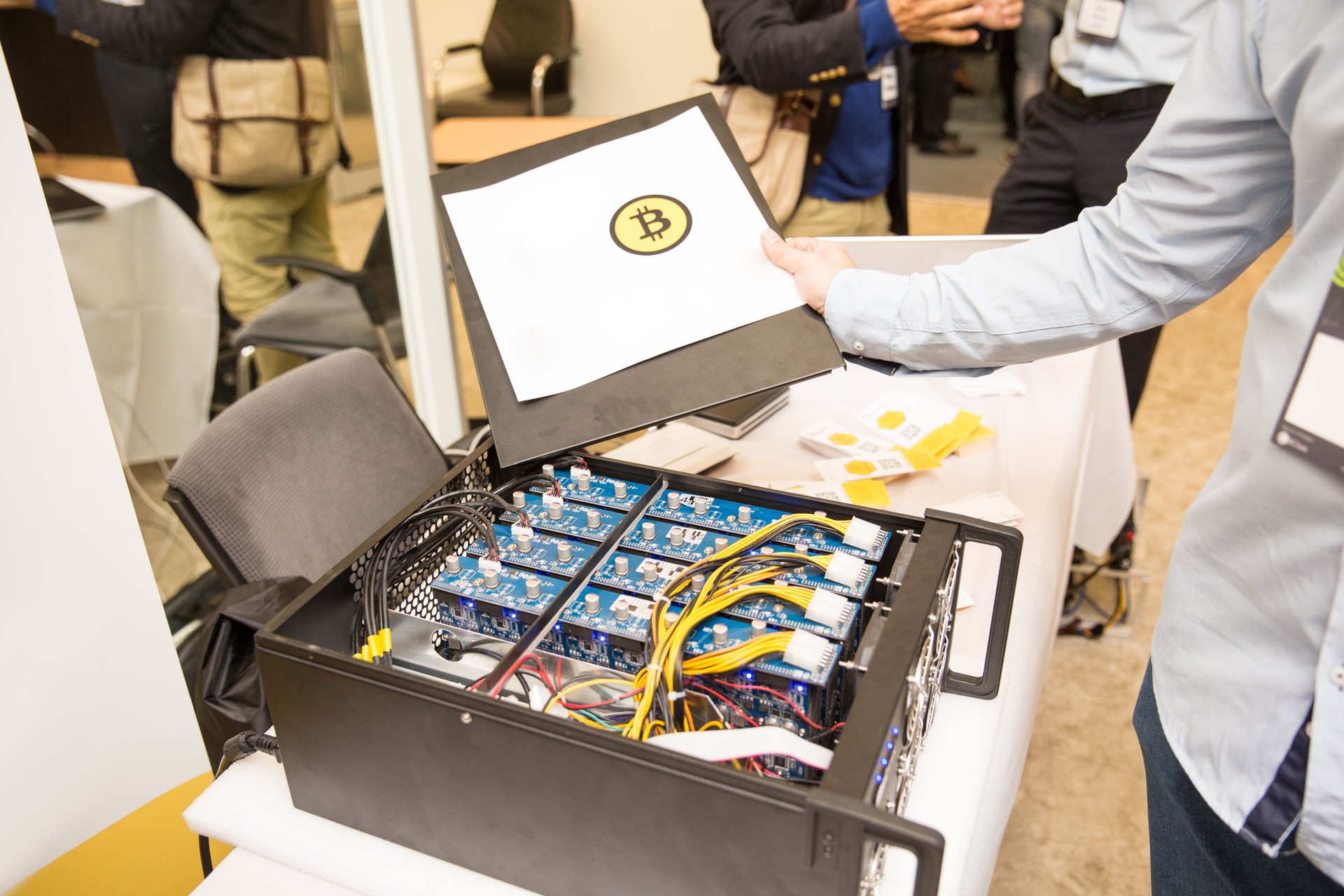 young computer engineer showing the paper with the sign of bitcoin at cryptocurrency mining farm